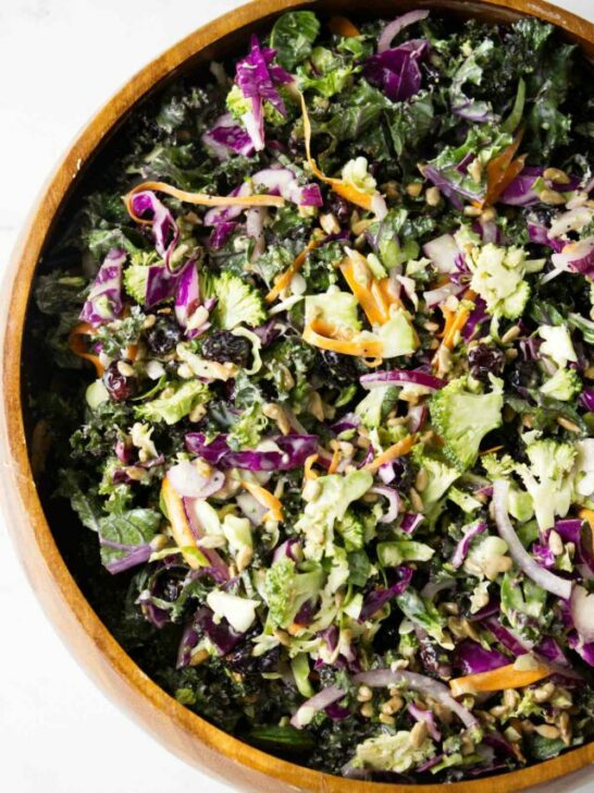 A wooden bowl filled with broccoli and kale salad.