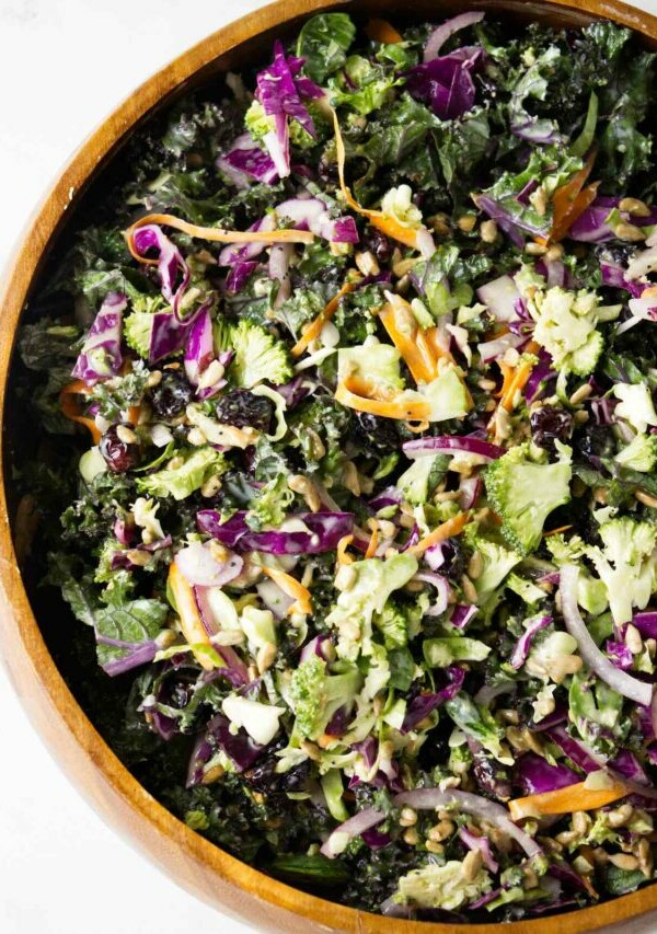 A wooden bowl filled with broccoli and kale salad.