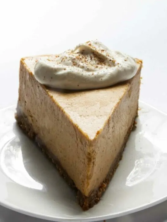 A slice of pumpkin cheesecake with whipped cream on top.