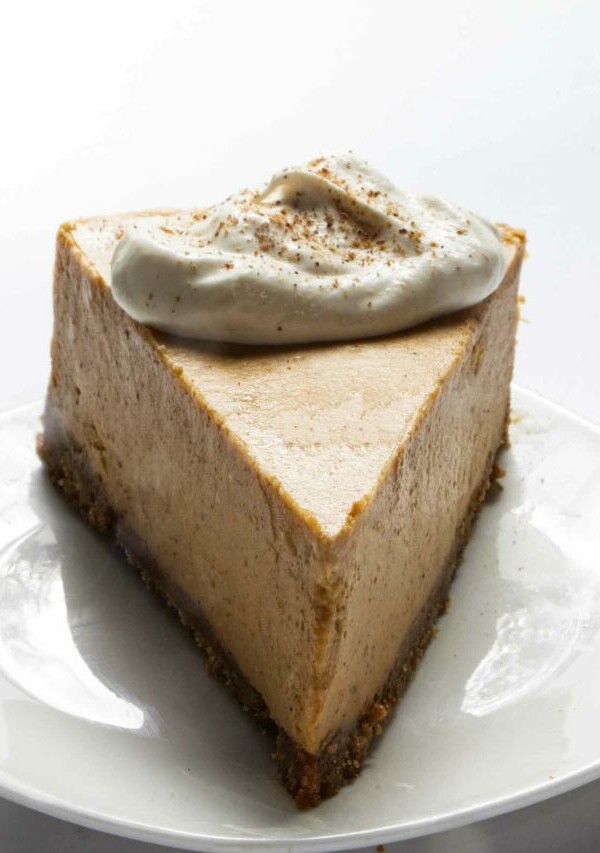 A slice of pumpkin cheesecake with whipped cream on top.