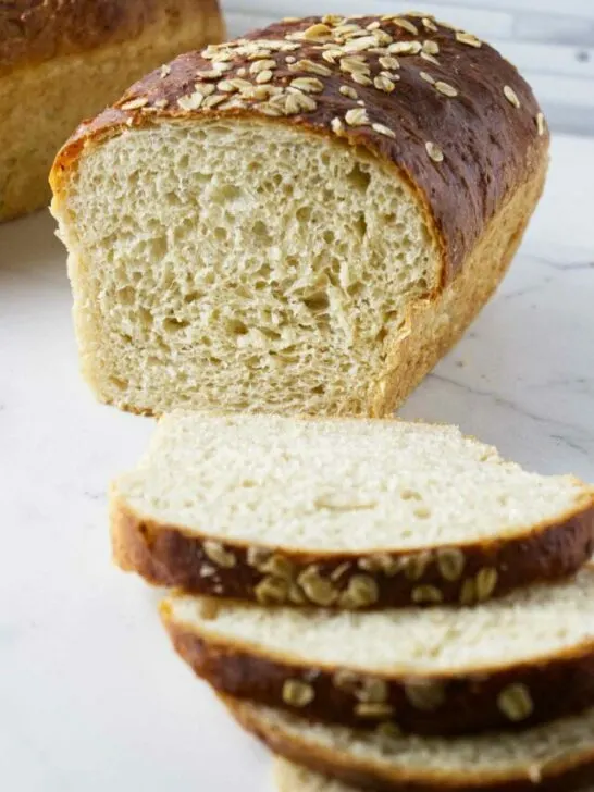 Slices of oatmeal bread in front of a loaf of bread.