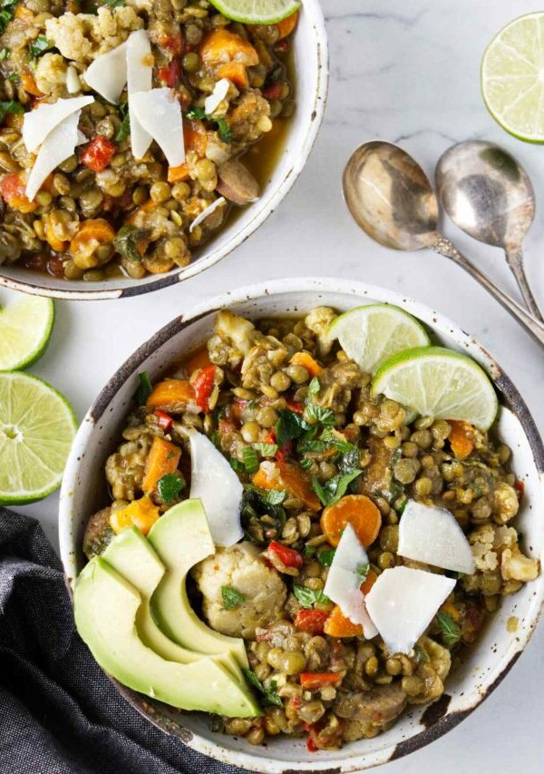 Two bowls of lentil stew next to soup spoons.