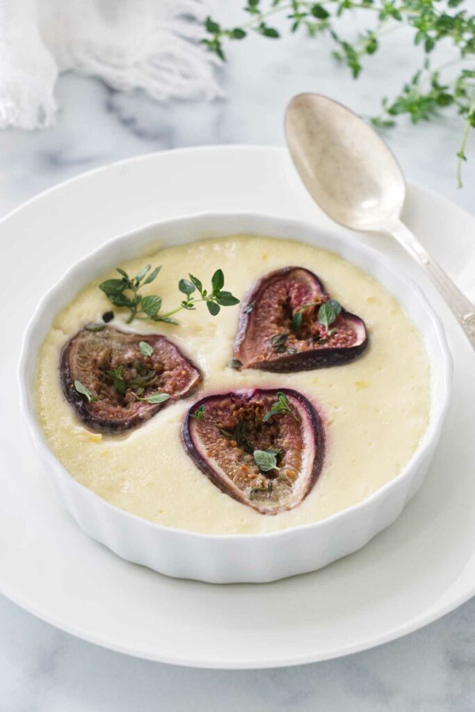 A serving of baked custard with roasted figs. A teaspoon next to the dish.