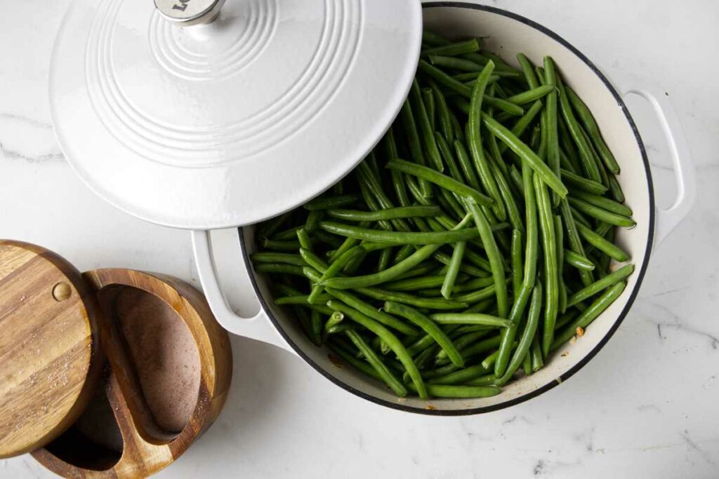 Cooking fresh green beans in a large skillet.