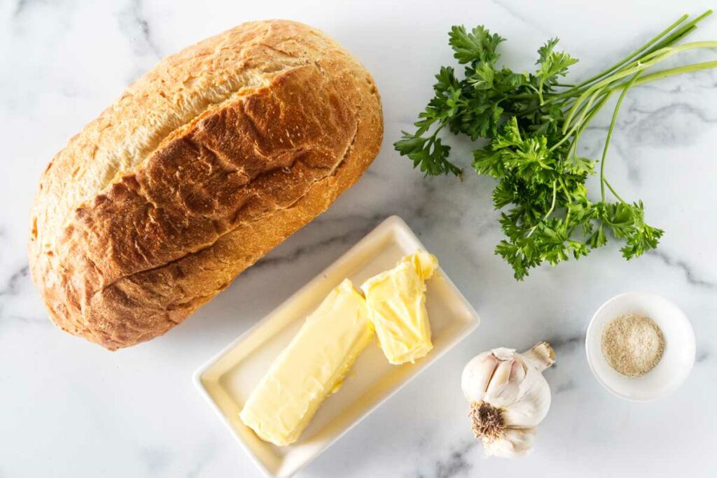 Recipe ingredients: Large loaf of bread, parsley, butter, garlic and garlic powder.