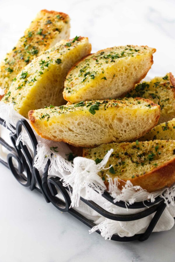 A wroght iron basket filled with hot garlic bread.