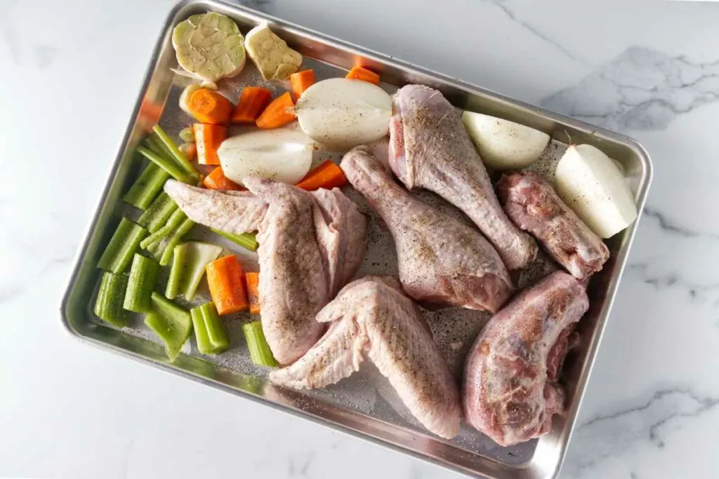 Turkey parts and vegetables on a sheet pan, ready to roast.