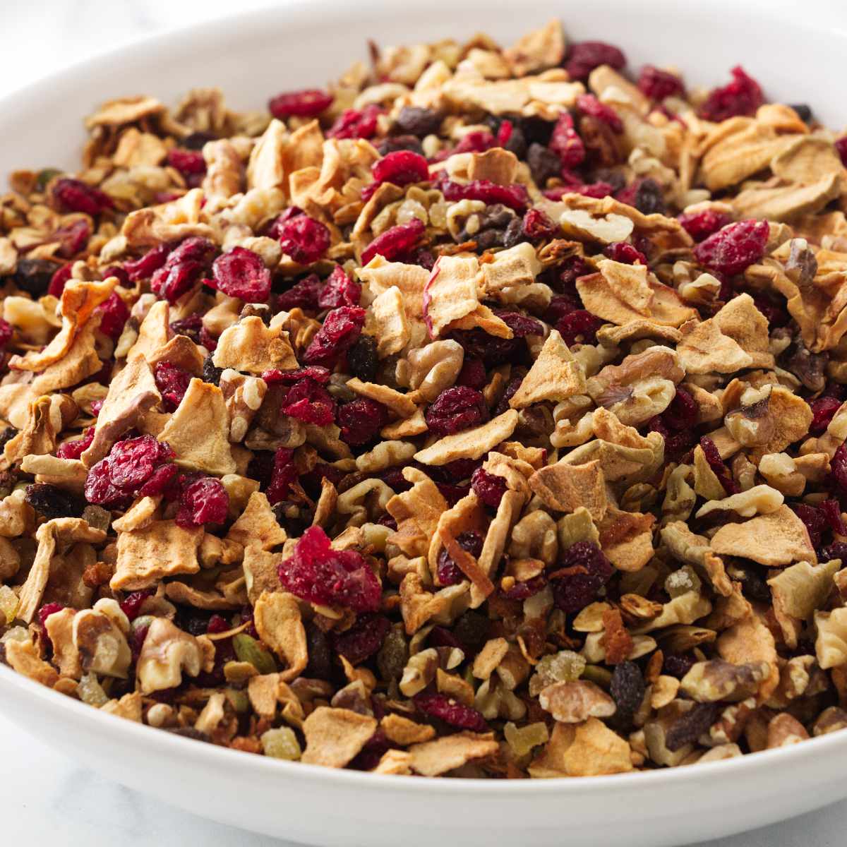 A bowl of granola with apples and cranberries.