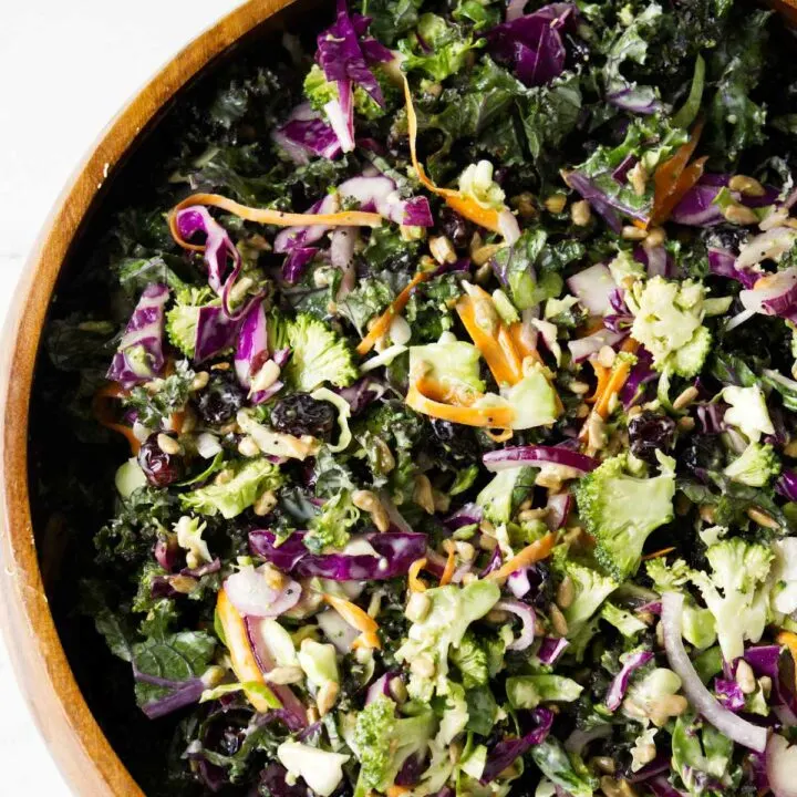 A wooden salad bowl filled with broccoli kale salad.