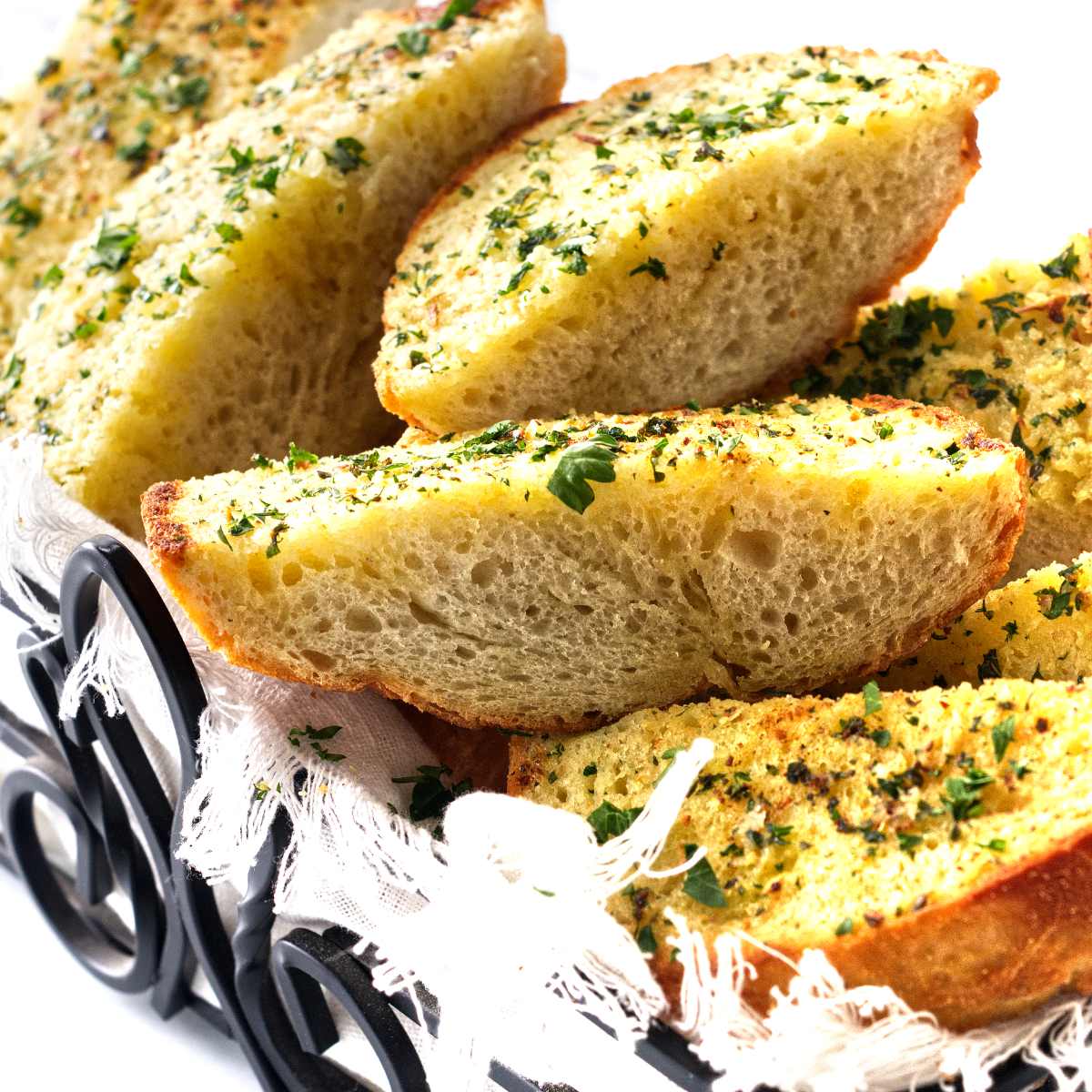 Buttery slices of bread in a black wroght iron bread basket.