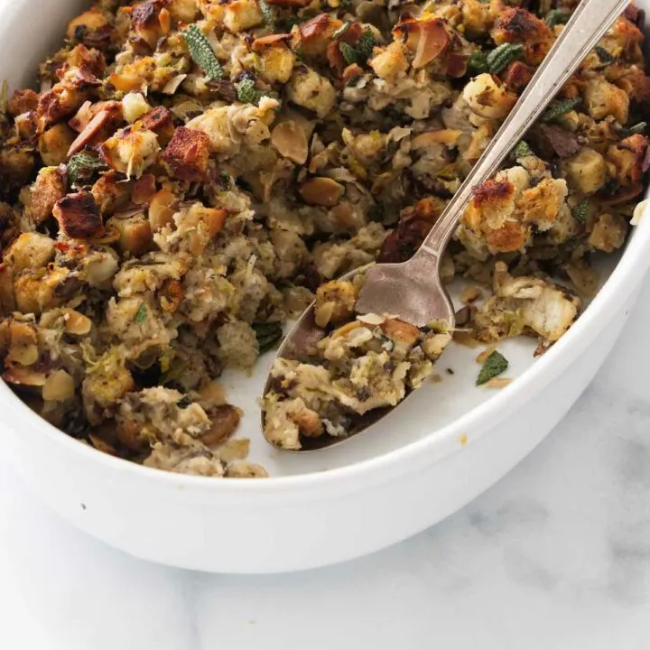 Close up view of a dish of baked stuffing and a serving spoon.