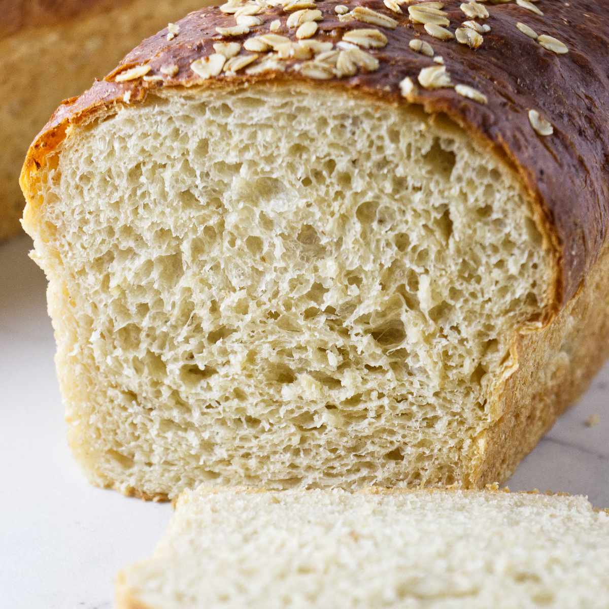 A loaf of oatmeal bread sliced in half to show the interior crumb.