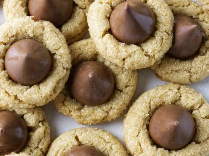 Several peanut butter blossoms on a white counter.