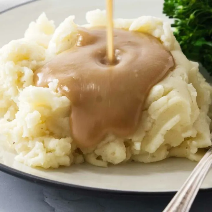 Gravy being poured over mashed potatoes.