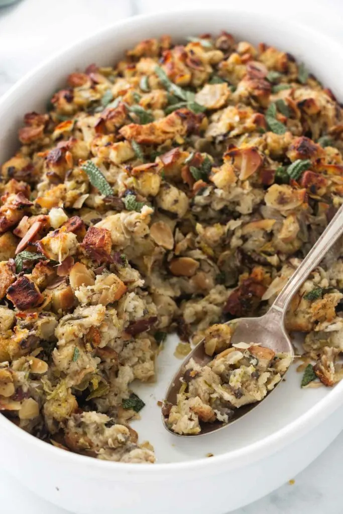 Close up view of a dish of baked stuffing and a serving spoon.