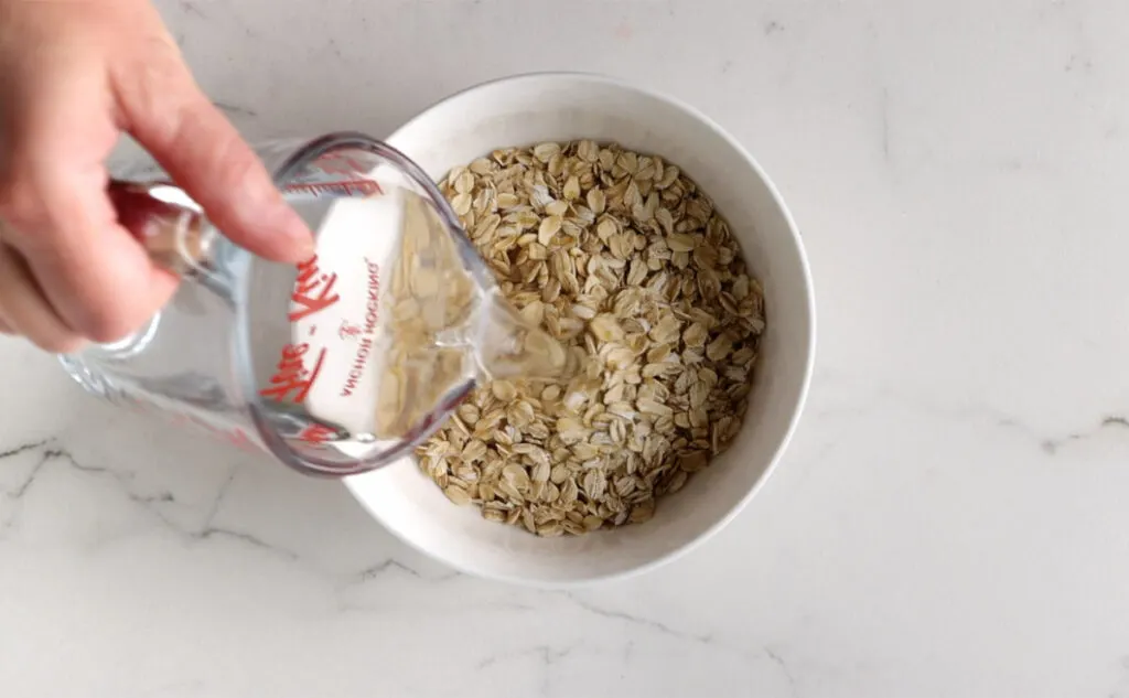Pouring boiling water into a bowl of rolled oats.