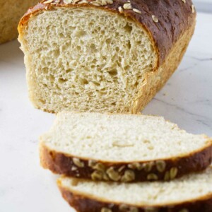 Slices of oatmeal bread in front of a loaf of bread.