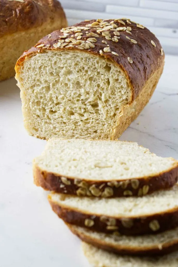 Slices of oatmeal bread in front of a loaf of bread.
