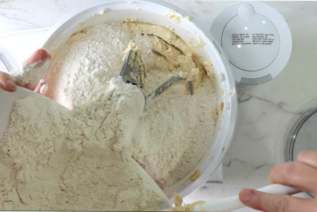 Adding flour to a stand mixer.