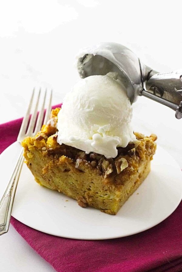 pumpkin bread pudding on a saucer with vanilla ice cream on top.