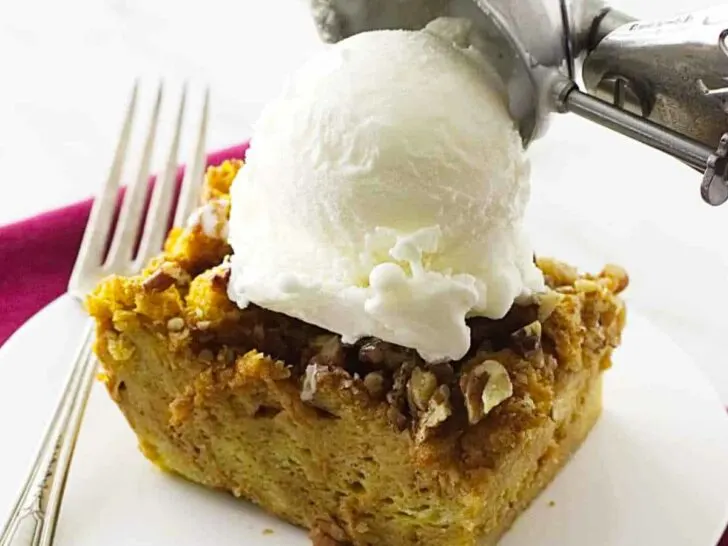 pumpkin bread pudding on a saucer with vanilla ice cream on top.