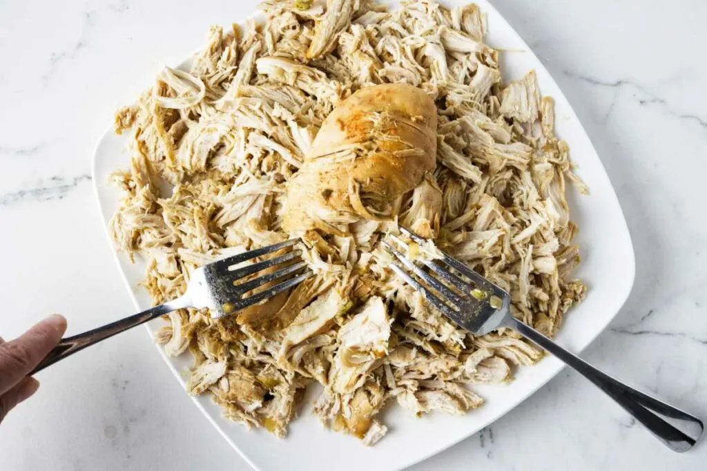 Shredding cooked chicken on a plate.