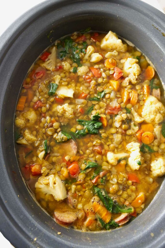 A slow cooker filled with freshly made lentil vegetable stew.