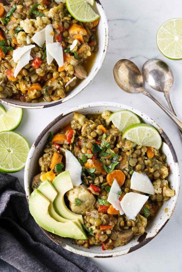 Two bowls of lentil stew next to soup spoons.