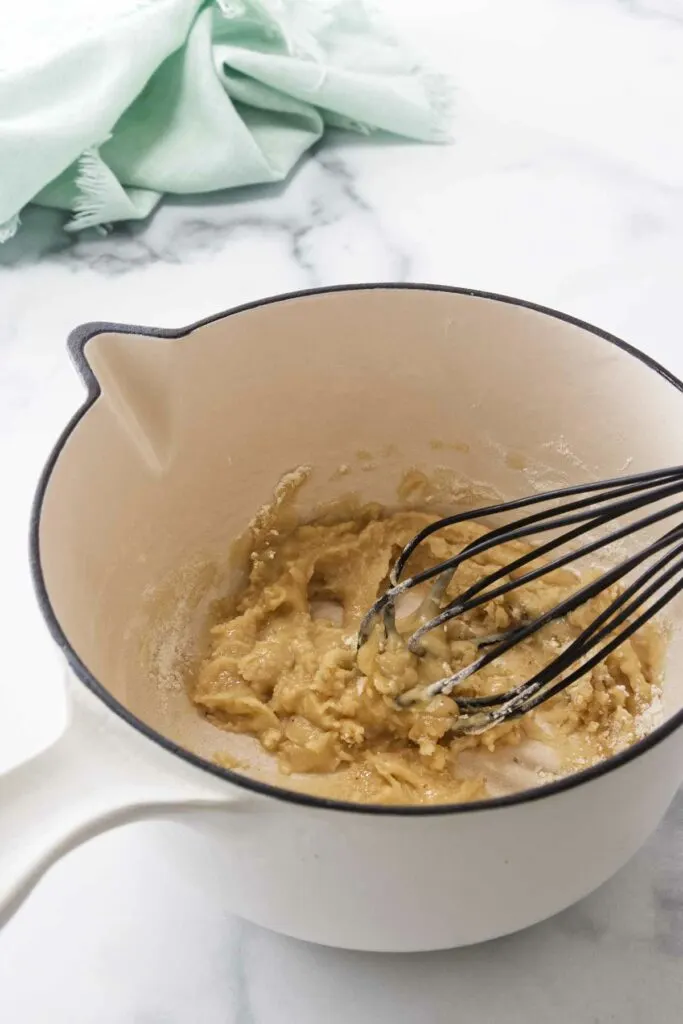 Whisking flour and turkey drippings in a saucepan.