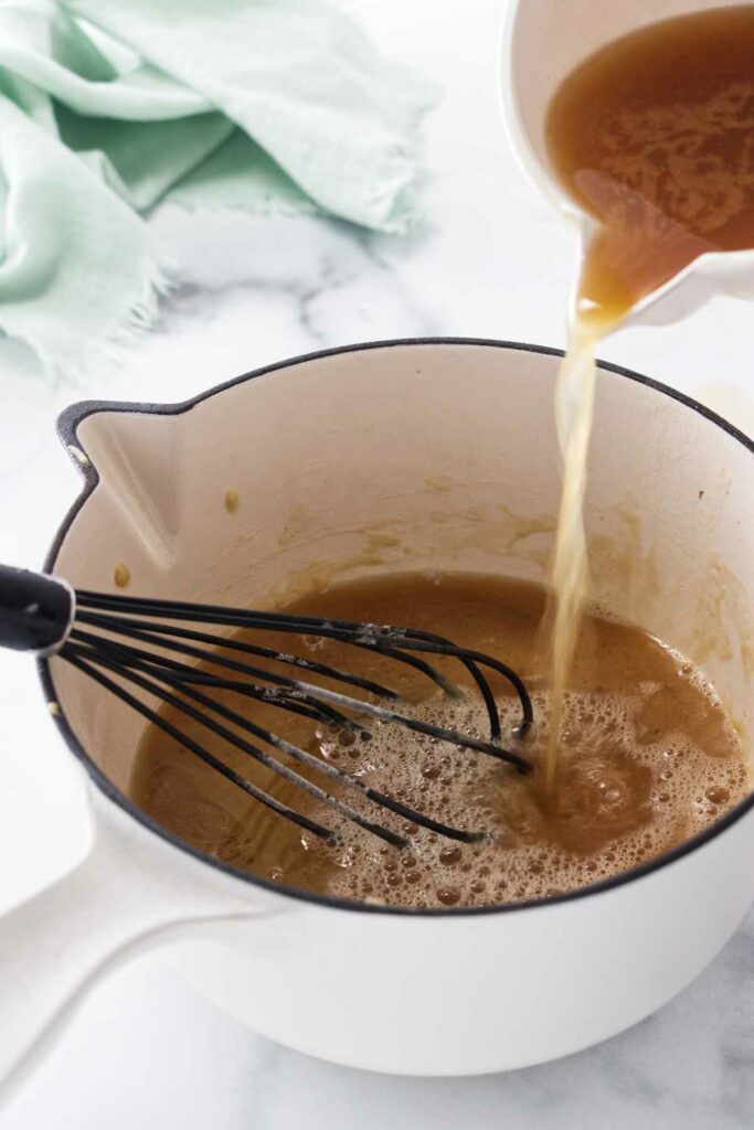 Pouring turkey drippings into a saucepan.