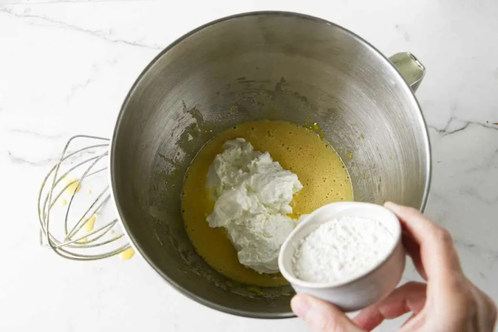 Adding yogurt and flour to the egg yolks mixture.