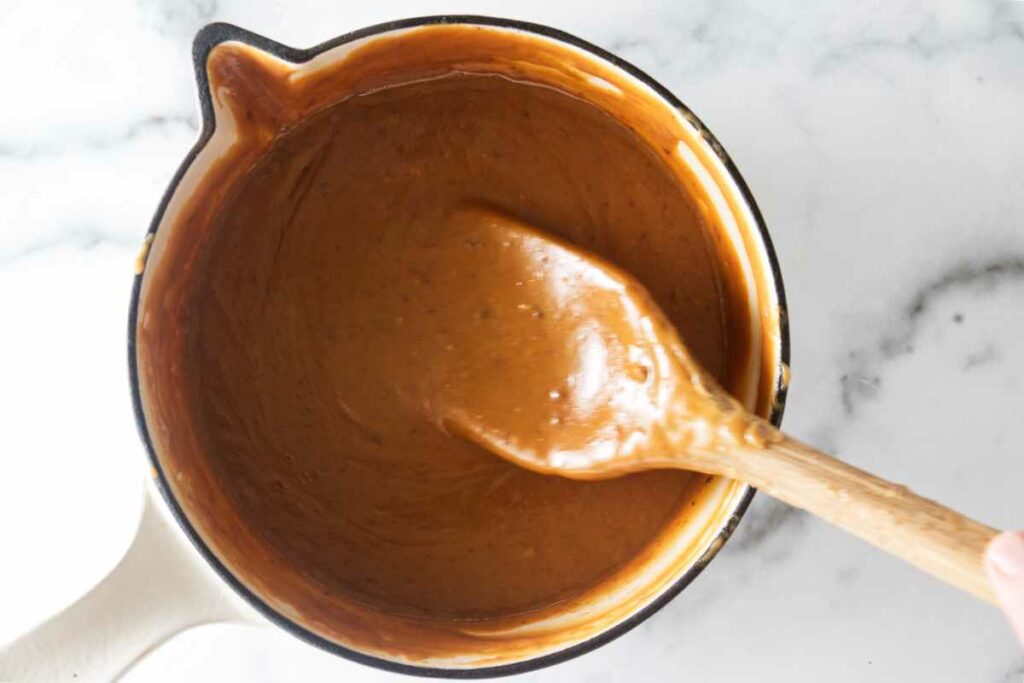 A pan of caramel and a wooden spoon.