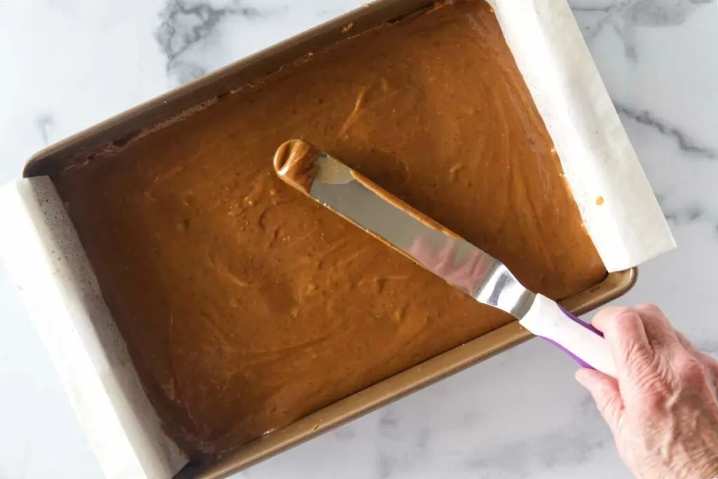Spreading caramel on a pan of cookies.