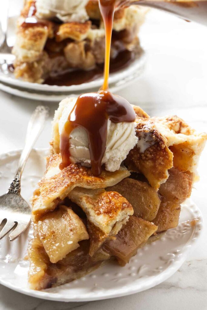 Drizzling caramel sauce over a slice of caramel apple pie.