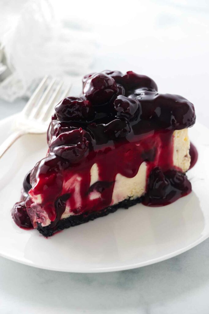 A slice of cherry cheesecake with cherry topping.