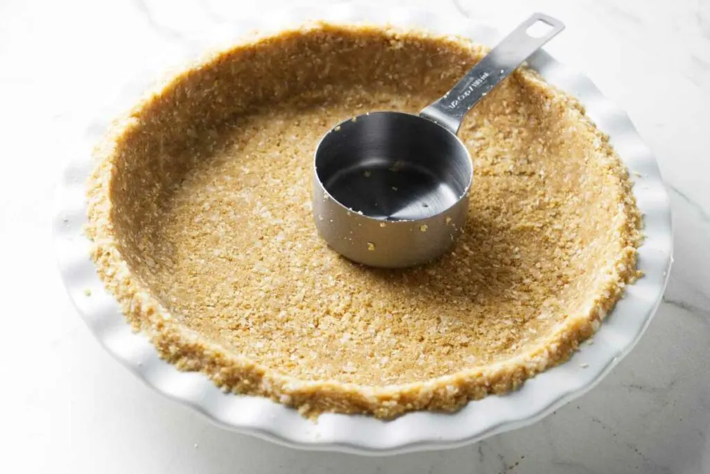Pressing a coconut cookie crust into a pie plate.