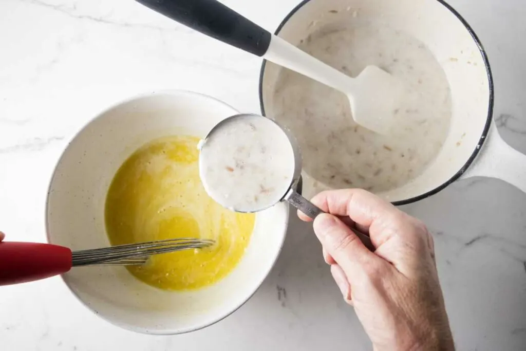 Tempering eggs with a hot milk mixture.