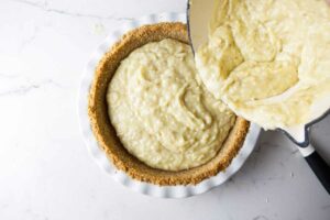 Pouring the coconut cream custard into a pie shell.
