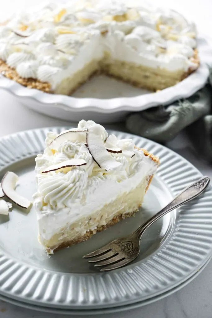 A slice of coconut cream pie on a plate with a fork.