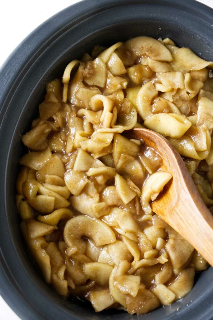 Homemade apple pie filling in a slow cooker pot.