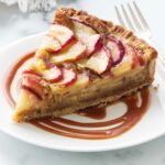 A slice of a frangipane tart on a plate.