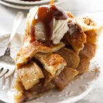 Vanilla ice cream and caramel sauce over a slice of caramel apple pie.