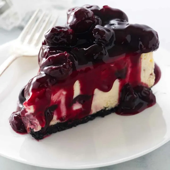 A slice of cherry cheesecake with cherry topping on a plate with a fork.