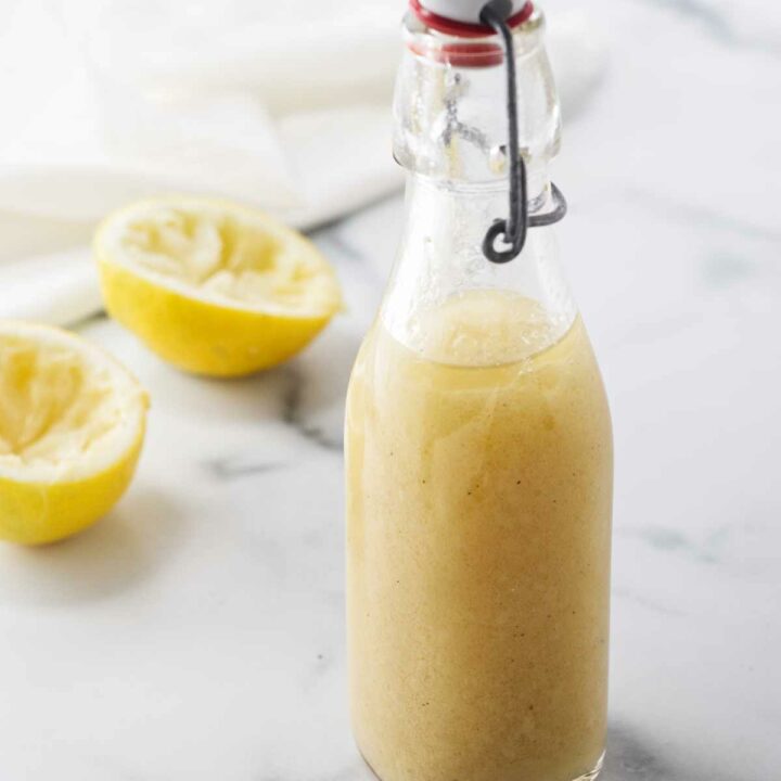 A bottle of homemade vinaigrette and two lemon rinds.