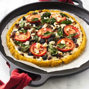 Baked polenta crust pizza on a cast iron pizza pan.