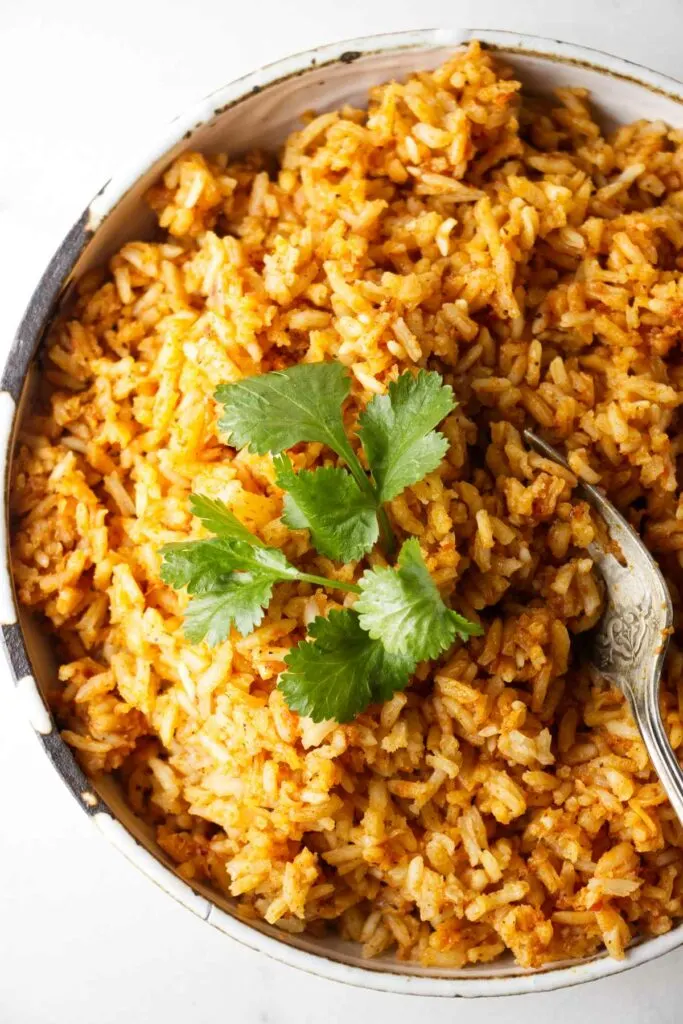 A serving bowl filled with Mexican red rice.