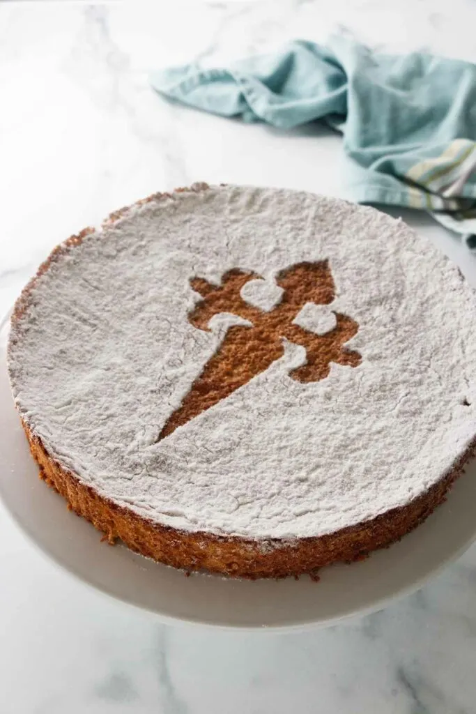 A sugar-dusted almond cake on a serving platter.