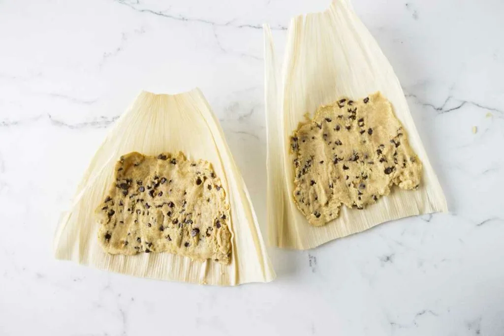 Spreading sweet masa dough on corn husks.