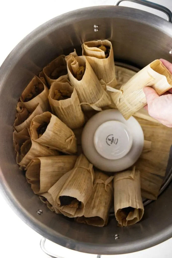 Cooking tamales in a large pot on the stove.