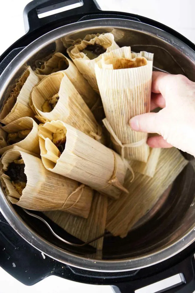 Adding tamales to an Instant Pot cooker.
